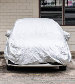 Veículo coberto com capa de proteção branca para proteger o carro. 