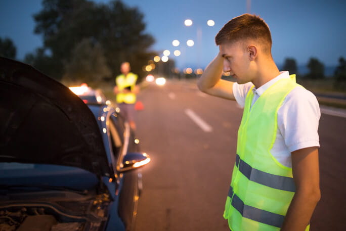 Homem com colete refletor, observa o acidente automóvel que envolve o seu carro