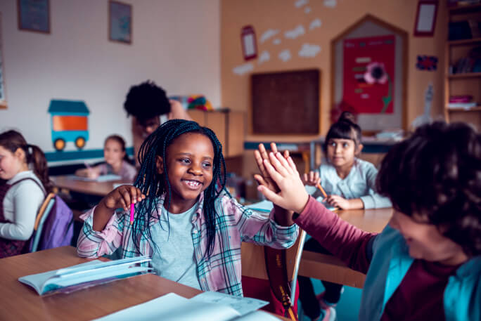 Crianças felizes na sala de aulas beneficiárias dos apoios do estado em 2023