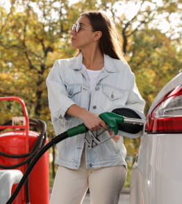 Mulher numa bomba de gasolina a abastecer o carro de combustível