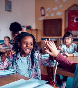 Crianças felizes na sala de aulas beneficiárias dos apoios do estado em 2023