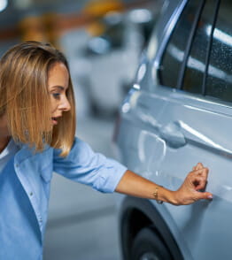 Antes de comprar um carro usado, uma mulher jovem examina o veículo.