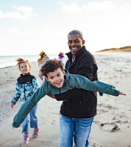Um pai brinca perto de dois filhos na praia, para sua proteção  