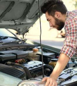 Homem examina o motor de um carro