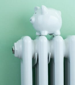 Porquinho-mealheiro em cima de um aquecedor, a simbolizar a redução do consumo de energia 