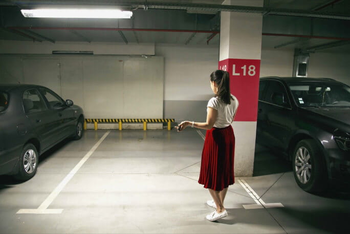 Mulher na garagem a pedir ajuda após o furto do seu carro parado 