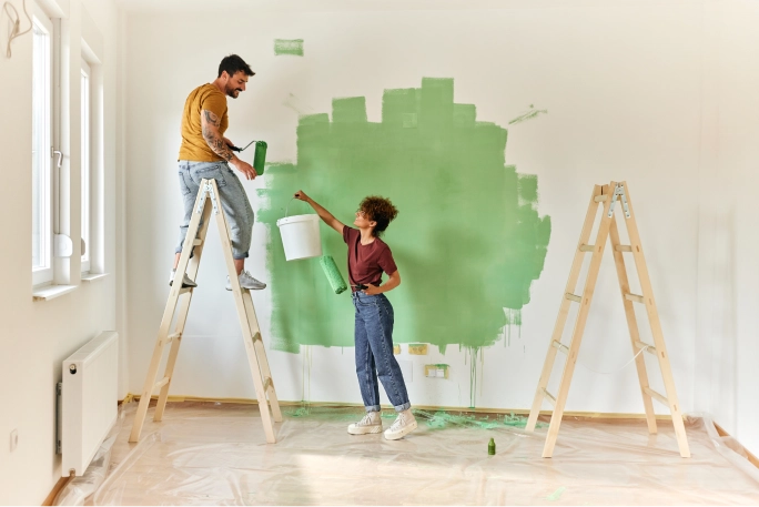 Jovem casal a pintar uma parede da sua casa nova