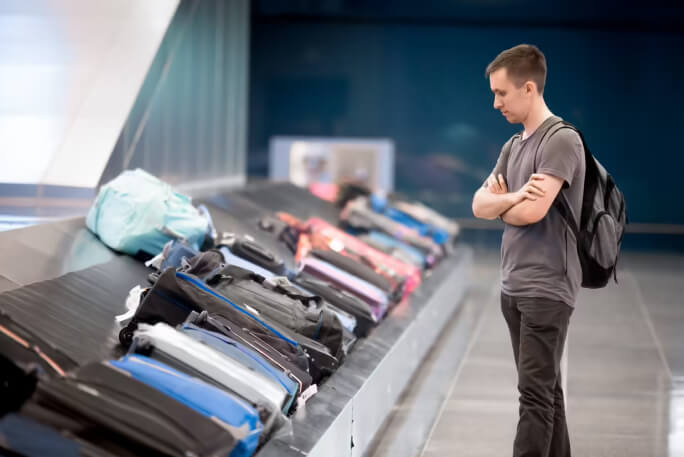 Um homem aguarda pela sua bagagem no aeroporto.