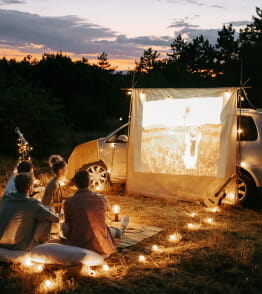 Grupo de amigos em férias de verão assiste a uma sessão de cinema privada ao ar livre. 