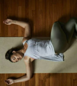 Mulher a fazer postura de descanso de yoga.