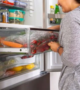 Mulher organiza o frigorífico para melhor conservação dos alimentos.