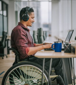 Pessoa com deficiência, sentada numa cadeira de rodas, trabalha online. 