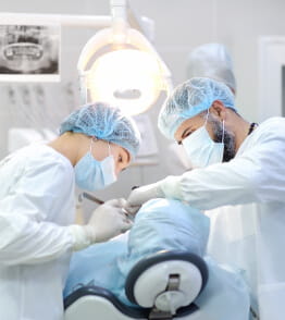 Equipa médica coloca implantes dentários num paciente, num consultório de um médico dentista. 