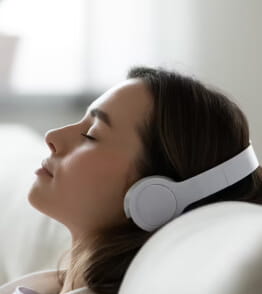 Mulher usa musicoterapia através de headphones.