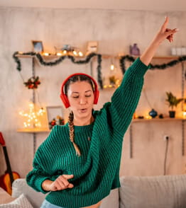 Mulher jovem de headphones dança ao ouvir músicas de Natal.