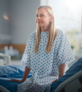 Paciente mulher sorri e descansa numa cama de hospital