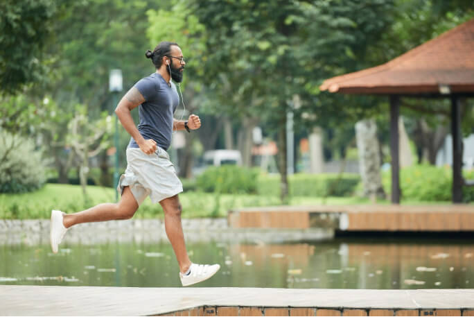 Homem a correr num parque ao lado de um lago