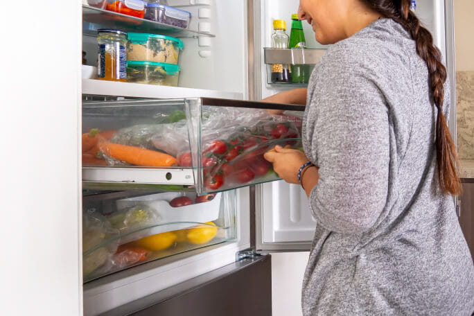 Mulher organiza o frigorífico para melhor conservação dos alimentos.
