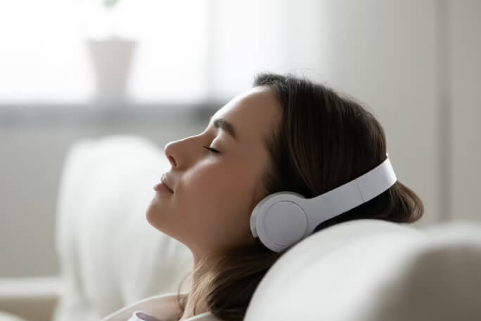 Mulher usa musicoterapia através de headphones.
