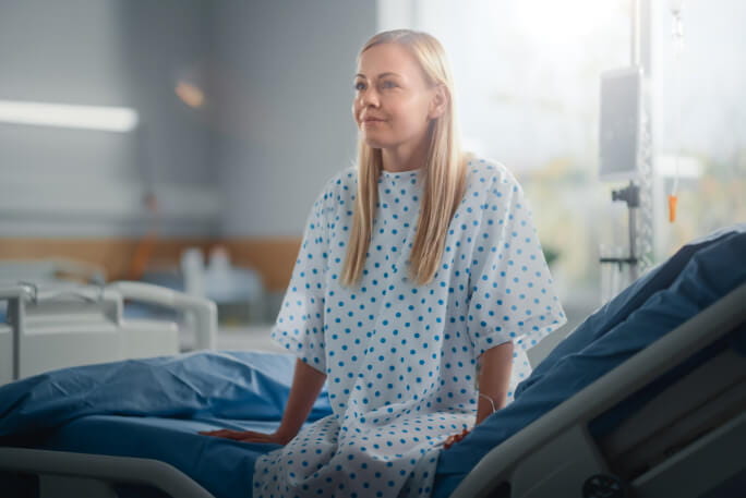Paciente mulher sorri e descansa numa cama de hospital